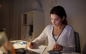 business, accounting, overwork, deadline and people concept - woman with tax form and calculator working at night office